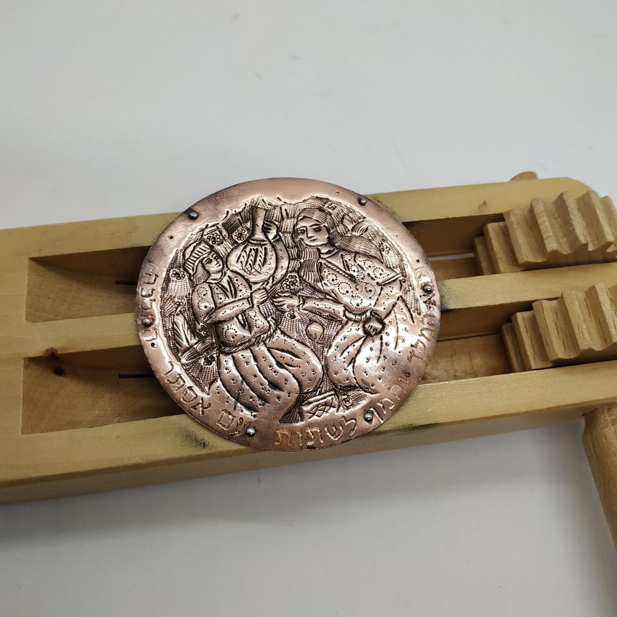 The engravings on Purim Grogger pine wood are handmade & hammered copper silver plated showing queen Esther at the dinner she invited the king.