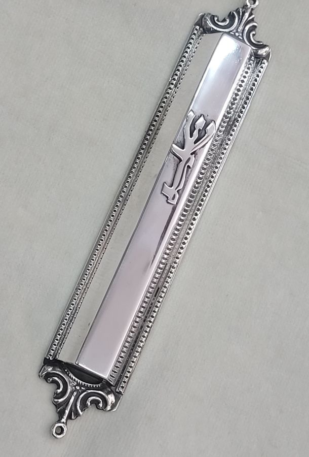 Handmade sterling silver Mezuzah trapeze shape with carvings on top and bottom of Mezuzah. Dimension 1.5 cm X 15 cm X 3 cm approximately.